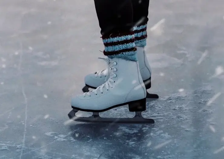 vertical-closeup-person-white-skates-ice-snowfall_181624-32694